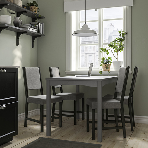 Juego de comedor de madera HAUGA gris, pequeño, con 4 sillas acolchadas junto a la ventana.