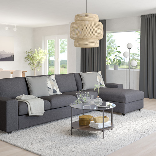 Sala de estar moderna con sofá gris, almohadas, lámpara colgante, mesa de centro, ventana y alfombra.