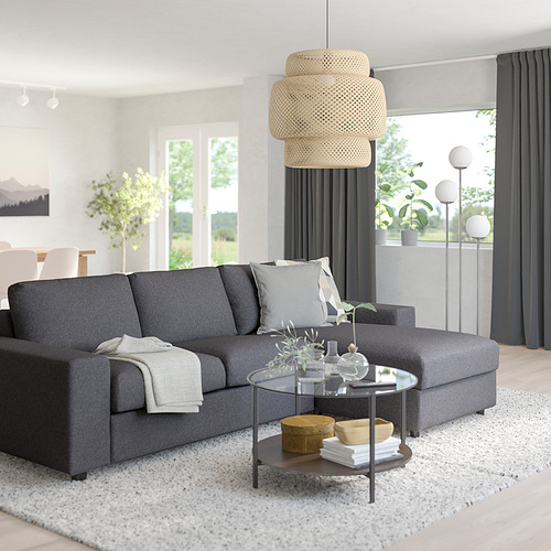 Salón moderno: sofá modular VIMLE gris, lámpara colgante tejida, mesa de centro de cristal, alfombra blanca, gran ventanal, cortinas grises.