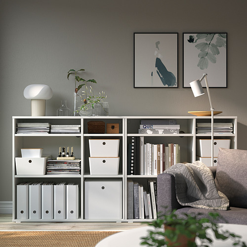 Sala de estar moderna con almacenamiento KUGGIS, libros, plantas, arte y un acogedor sofá.