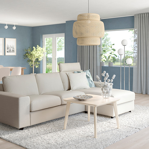 Sofá modular VIMLE beige en forma de L con mesa de centro, jarrón y lámpara colgante a juego contra la pared azul.