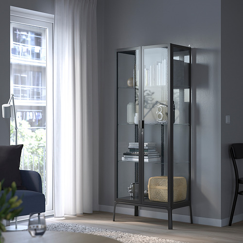 Sala de estar moderna con mueble con puerta de vidrio negro MILSBO que exhibe libros y decoración, estantes ajustables.