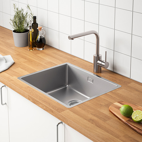Fregadero de cocina moderno con grifo de acero inoxidable, encimera de madera y decoración de botellas, limas y plantas.