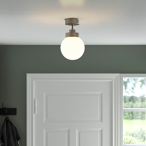 Una lámpara colgante con una pantalla de globo de vidrio ilumina una puerta blanca, proporcionando una iluminación equilibrada.