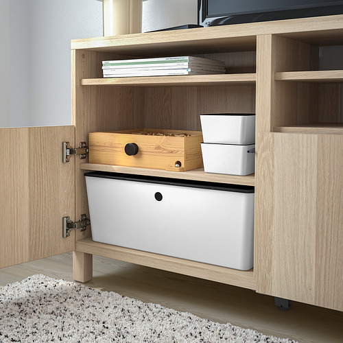 Armario de madera abierto que muestra el almacenamiento: papelera blanca grande, caja de madera, pequeñas papeleras blancas y libros en el estante superior.