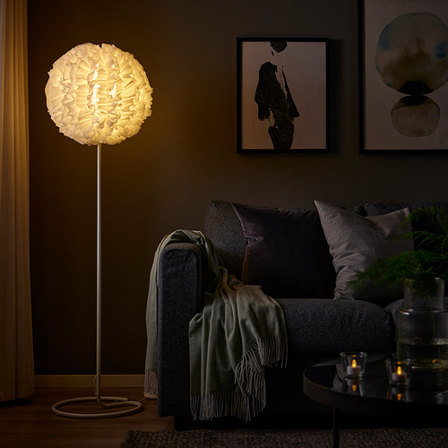Acogedora sala de estar con lámpara VINDKAST de luz baja, sofá gris y arte de pared.