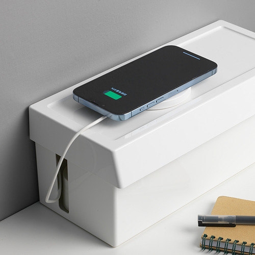 Un teléfono inteligente cargándose en una caja. La caja organiza los cables y oculta los conectores.