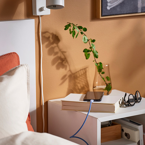 Acogedora habitación con cama, mesita de noche blanca y vibrante cable de carga LILLHULT de 3 m.