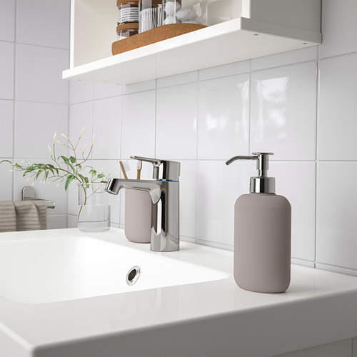 Baño moderno con lavabo blanco, grifo cromado brillante y dispensador de jabón de color púrpura rosado, EKOLN, colocado junto al soporte para cepillos de dientes.