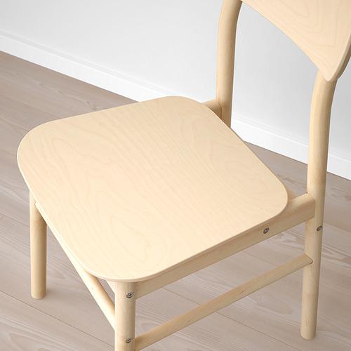Silla de madera ligera con asiento y respaldo lisos y redondeados, con textura de grano natural, colocada sobre un suelo de madera.