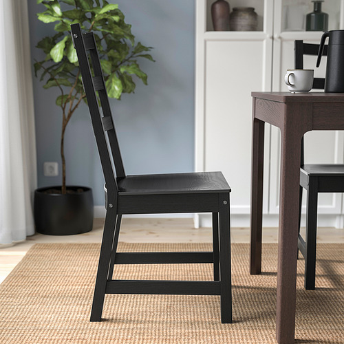Silla de madera negra con respaldo alto cerca de mesa de madera sobre alfombra.