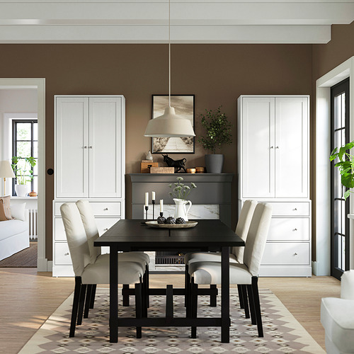Comedor moderno con mueble HAVSTA blanco, paredes marrones, mesa negra, sillas ligeras y alfombra.