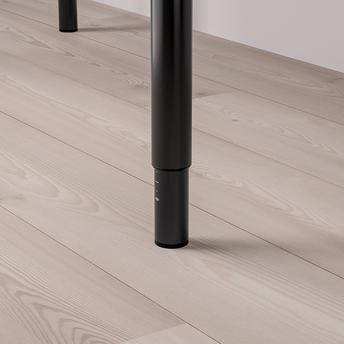 Pata de mesa de metal negro sobre suelo de madera clara.