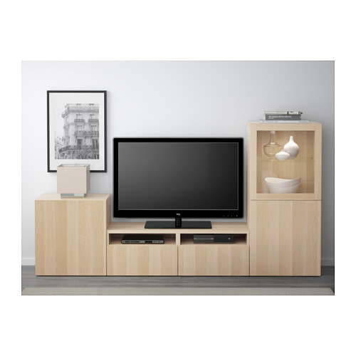 Mueble de tv moderno con madera clara, almacenamiento, estante amplio y cierre suave. La decoración incluye cuadros y jarrones.