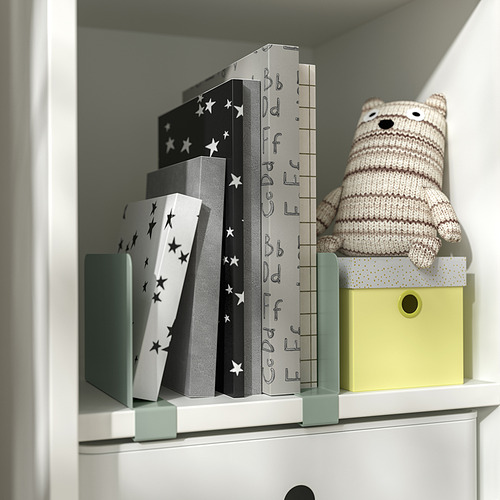 Estantería blanca con cajas negras con estampado de estrellas, osito de punto y sujetalibros RELATERA en caja amarilla.