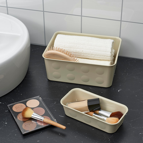 Encimera de baño con mármol negro, organizador beige con toallas y cepillos, y artículos de maquillaje.