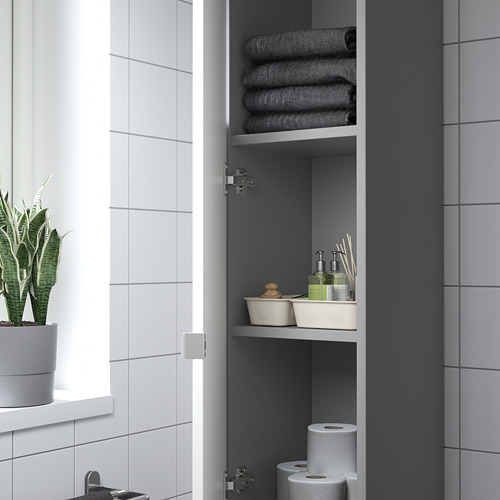 Armario de baño con puerta abierta que muestra toallas dobladas, artículos de tocador y rollos de papel higiénico en los estantes.