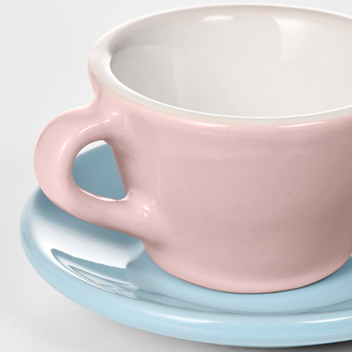 Primer plano de la taza rosa de los niños en un platillo azul claro, suave y bien hecho.