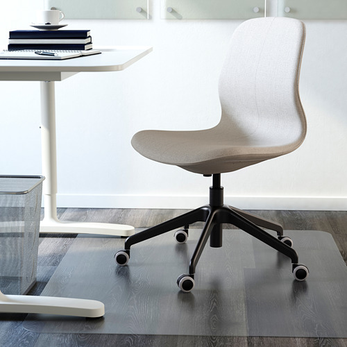 Silla de oficina gris con ruedas en escritorio blanco, libros y taza.