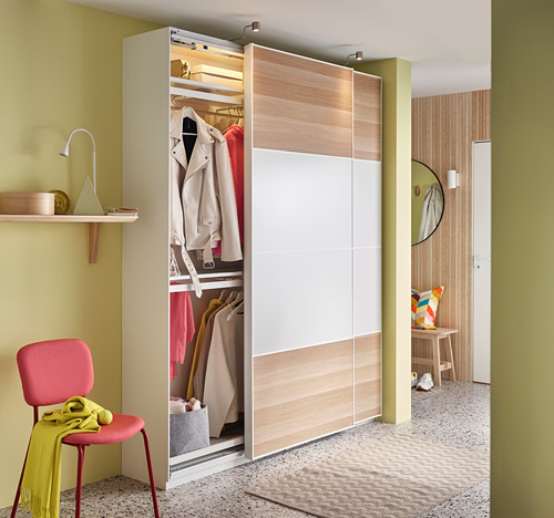 Habitación moderna con paredes amarillas, piso de madera, closet abierto, silla con mantel verde.