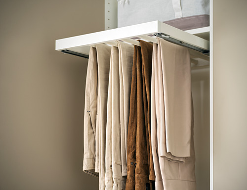 Percha de pantalón KOMPLEMENT, blanca, metal, sostiene pantalones beige, organizada.