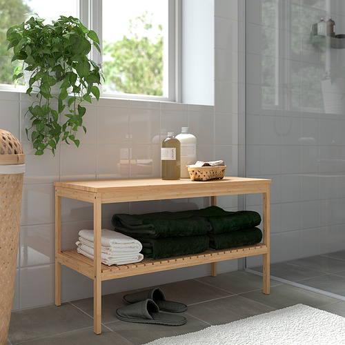 Estantería de baño de bambú con toallas, botellas, planta y zapatillas.