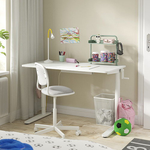 Una configuración de escritorio blanca para niños con una silla giratoria, un estante y accesorios.