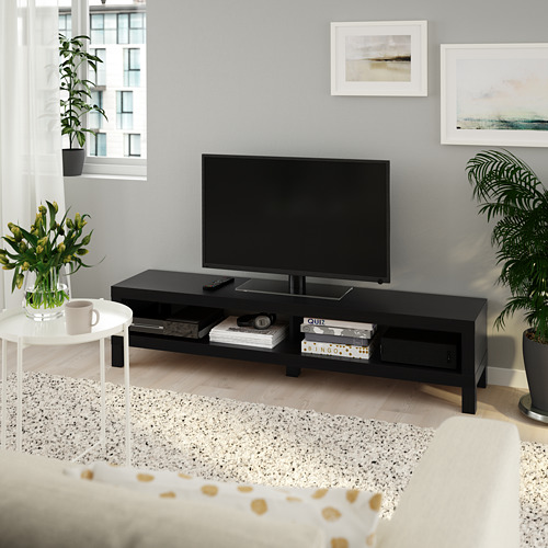 Sala de estar moderna con soporte de TV bLACK, planta, mesa auxiliar, alfombra y sofá debajo de obras de arte.