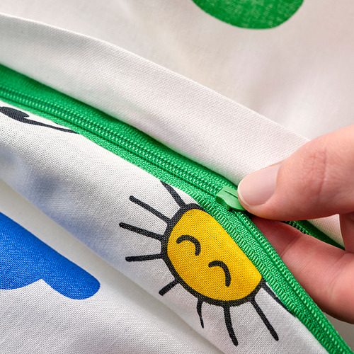 Una mano abriendo una funda nórdica con cremallera verde con un sol amarillo y una nube azul.