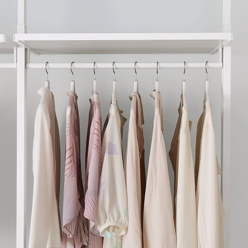 Un armario con ganchos para colgar que organizan la ropa de manera ordenada en perchas blancas, utilizando el espacio completo desde el piso hasta el techo.