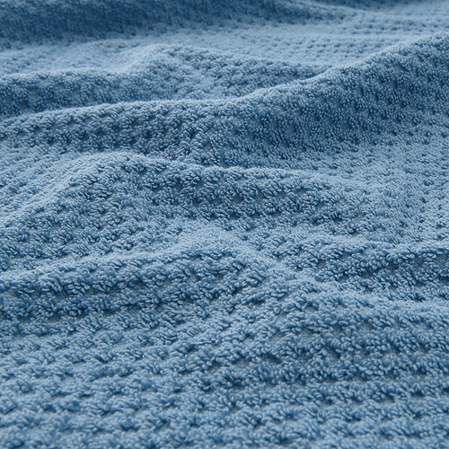 Primer plano de una toalla azul suave y texturizada, que muestra su tejido esponjoso y absorbente.