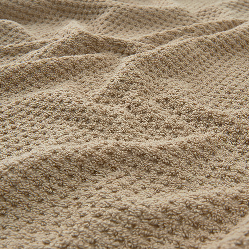 Toalla de algodón beige texturizada, visualmente suave y esponjosa, que muestra un patrón de tejido intrincado.