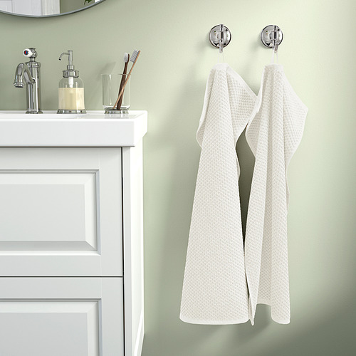 Baño ordenado con paredes verdes, toalla beige en gancho cromado.