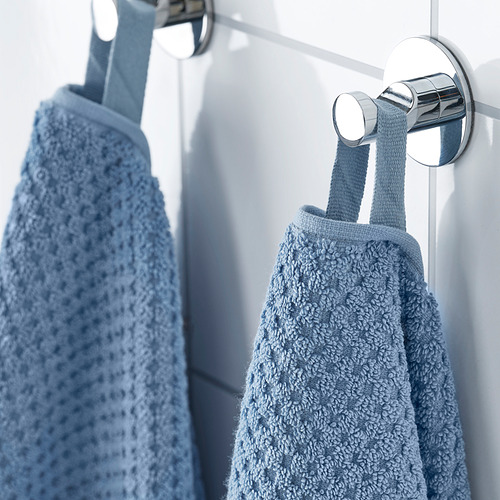 Dos suaves toallas azules cuelgan de una barra de metal moderna, una doblada para su absorción.