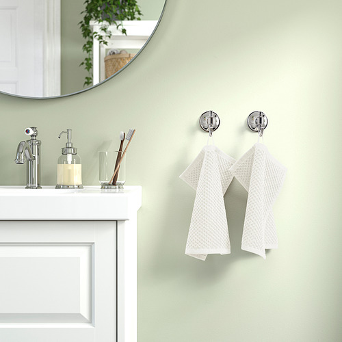 Baño con paredes verdes, lavabo blanco, toallas GULVIAL y espejo que refleja la vegetación.