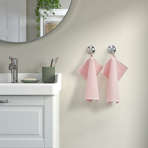 Baño con toallas GULVIAL rosas sobre ganchos cromados junto al lavabo.