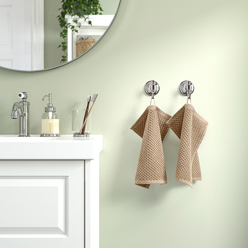 Las toallas de algodón GULVIAL beige cuelgan de ganchos de pared cerca del lavabo y el espejo blancos, mostrando una textura suave y esponjosa y un grosor medio.