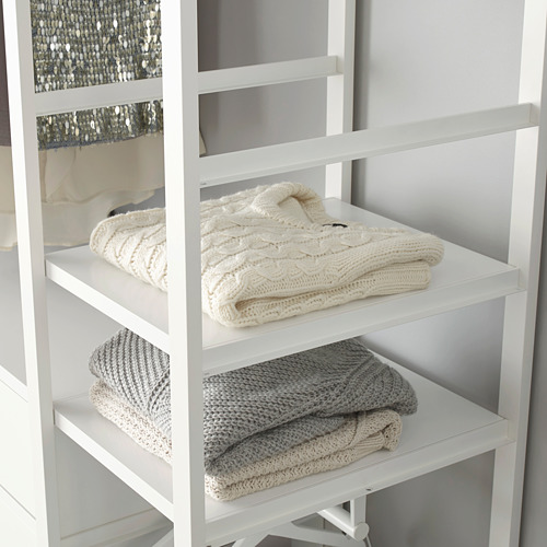 Mantas plegadas sobre tres estantes blancos en un mueble de almacenaje modular.