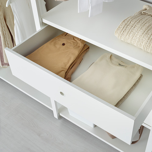 Cajón abierto de mueble de almacenamiento ELVARLI blanco que muestra pantalones beige cuidadosamente doblados y un suéter beige.