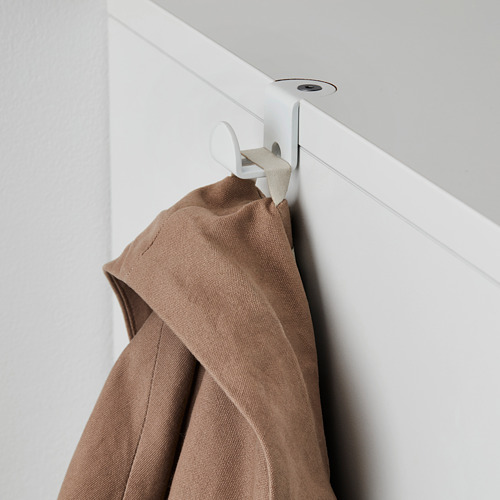 El abrigo marrón cuelga de un gancho de pared blanco, parte del sistema de almacenamiento GALANT.