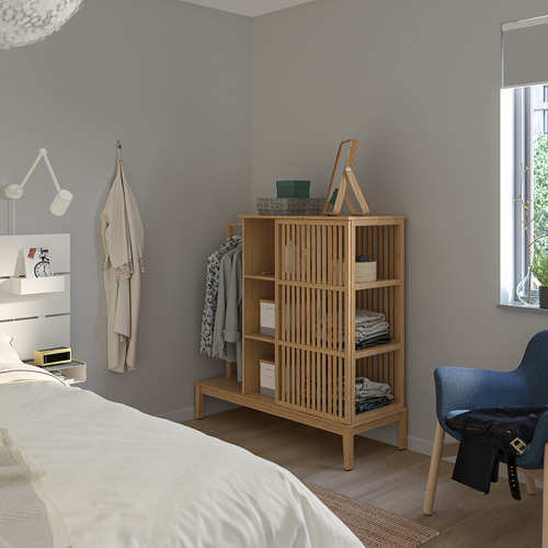 Dormitorio minimalista con armario NORDKISA, perchero, silla azul y cama con sábanas blancas.