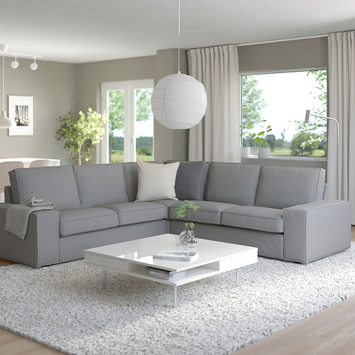 Sala de estar moderna con un gran sofá seccional KIVIK gris, mesa de centro blanca y gran ventanal.