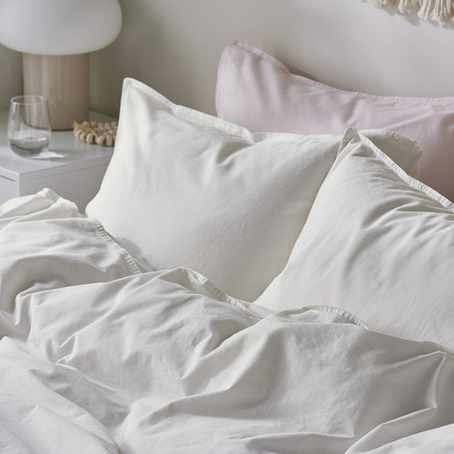 Acogedora cama con edredón y almohadas de algodón liso, blanco y de alta calidad. Suave, acogedor y cuidadosamente arreglado con detalles sutiles.