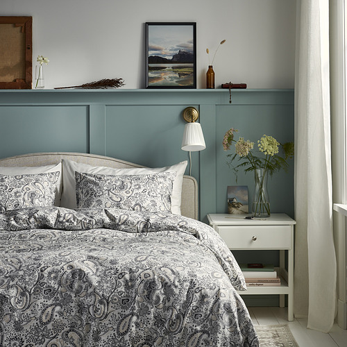 Dormitorio azul con cama de cachemira blanca, mesita de noche y flores.