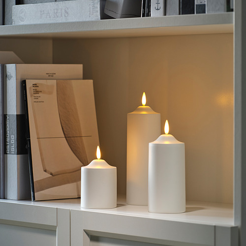 Tres velas SMÅLOM led en tamaños pequeño, mediano y grande en estantería, diseño minimalista, ambiente acogedor.