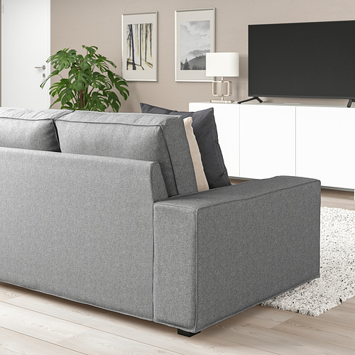Sala de estar moderna con un gran sofá KIVIK gris, cojines oscuros, TV de pantalla plana, gabinete blanco y planta. El sofá es espacioso y tiene capacidad para varios asientos.