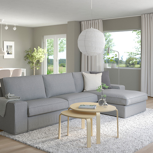 Sala de estar moderna, un gran sofá seccional gris KIVIK con una otomana a juego, una elegante mesa de centro de madera y una lámpara colgante de linterna de papel blanco.