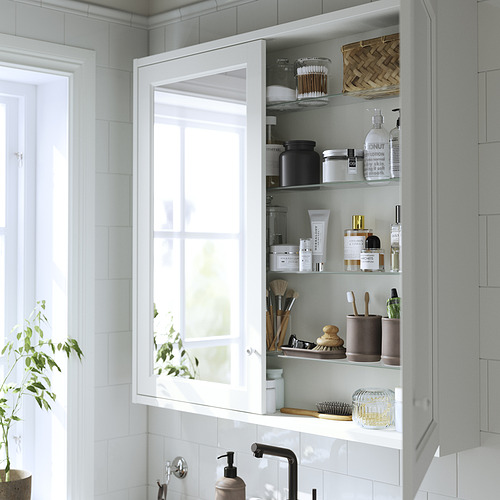 Un mueble de baño de pared con puertas de espejo que muestra artículos de tocador y productos de belleza en estantes de vidrio.