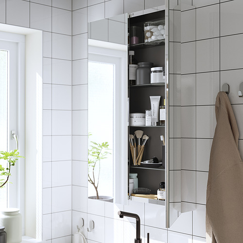 Armario con espejo montado en la pared con puerta abierta que revela artículos de tocador y brochas de maquillaje, mejorando el espacio con reflejos.