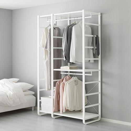 Perchero ELVARLI blanco con prendas colgadas y estanterías junto a la cama.